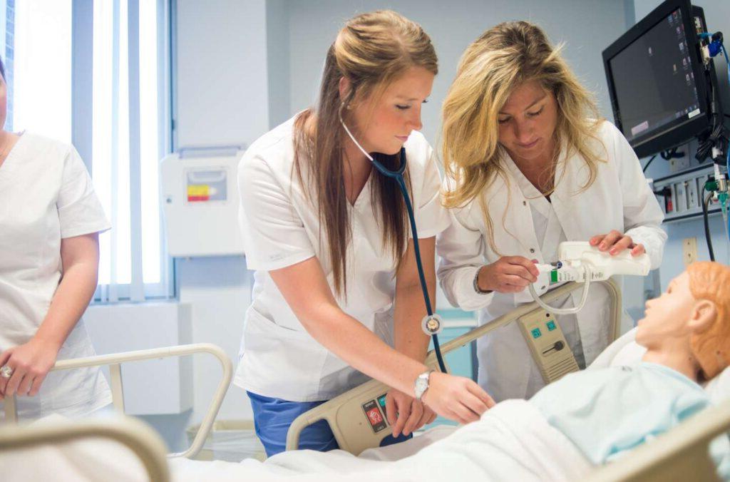 Two nursing students take the temperature of a child.